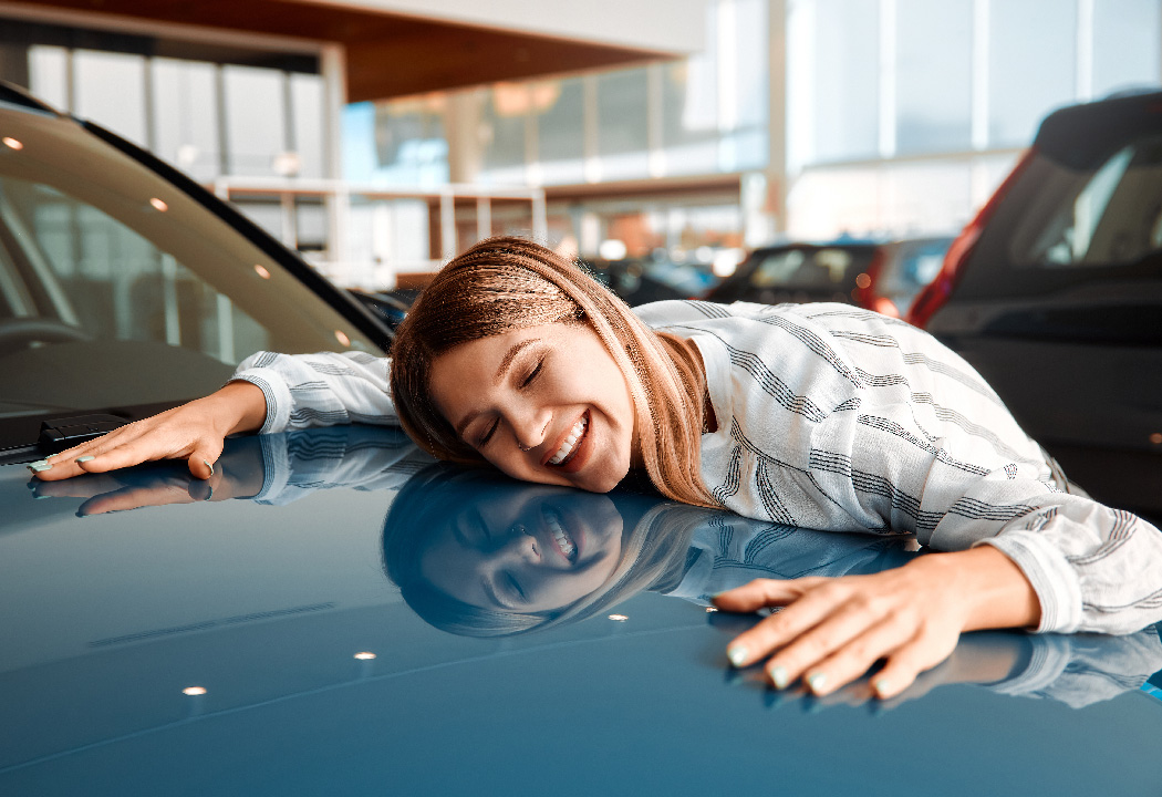 Woman hugs a car she wants to purchase