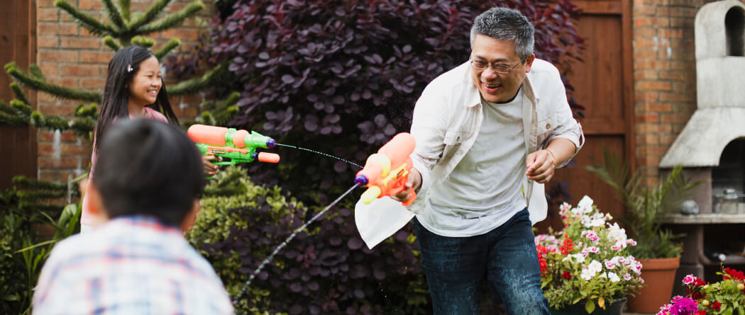 Dad and kids playing outside with water guns