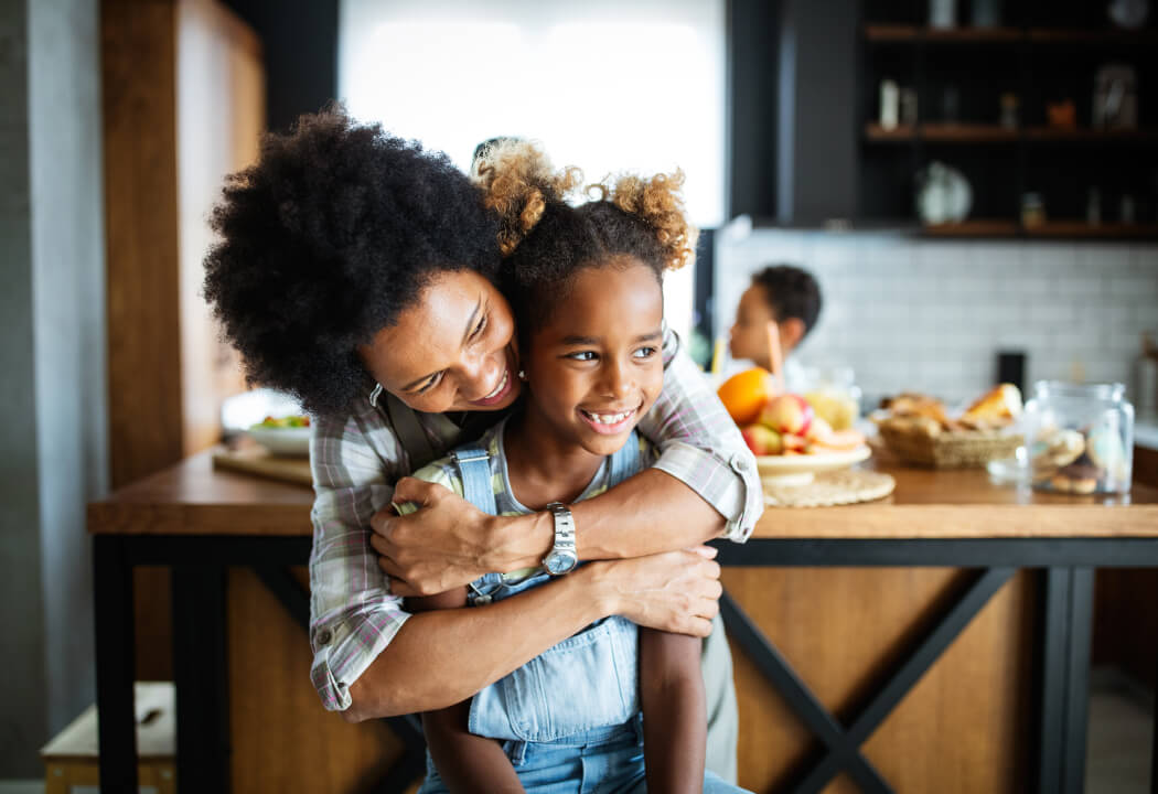Mom and tween daughter hugging in a kitchen